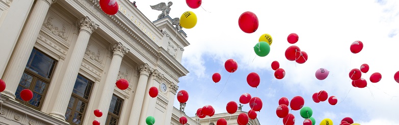 Bild på universitetshuset med ballonger i luften.